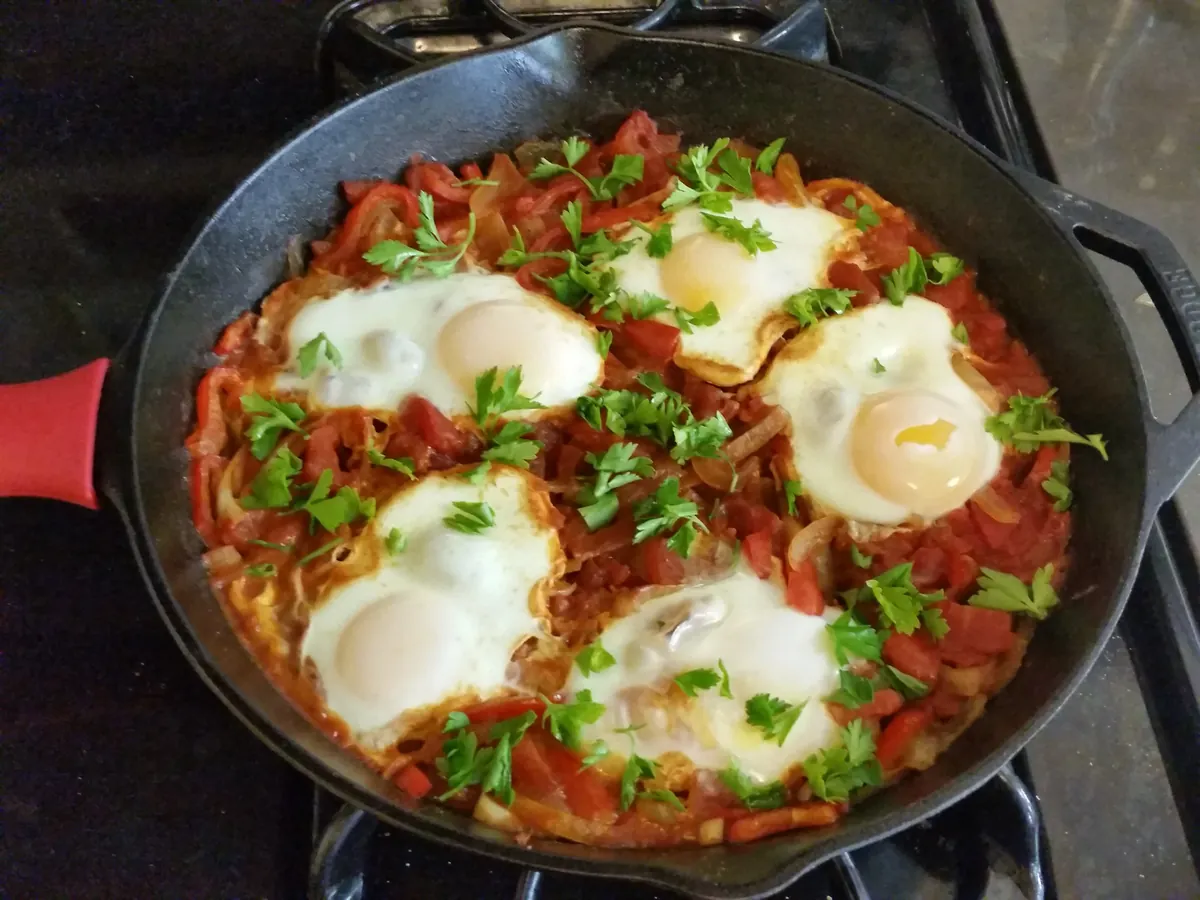Shakshuka, in Tomatensauce pochierte Eier mit Paprika und Kräutern in einer Pfanne