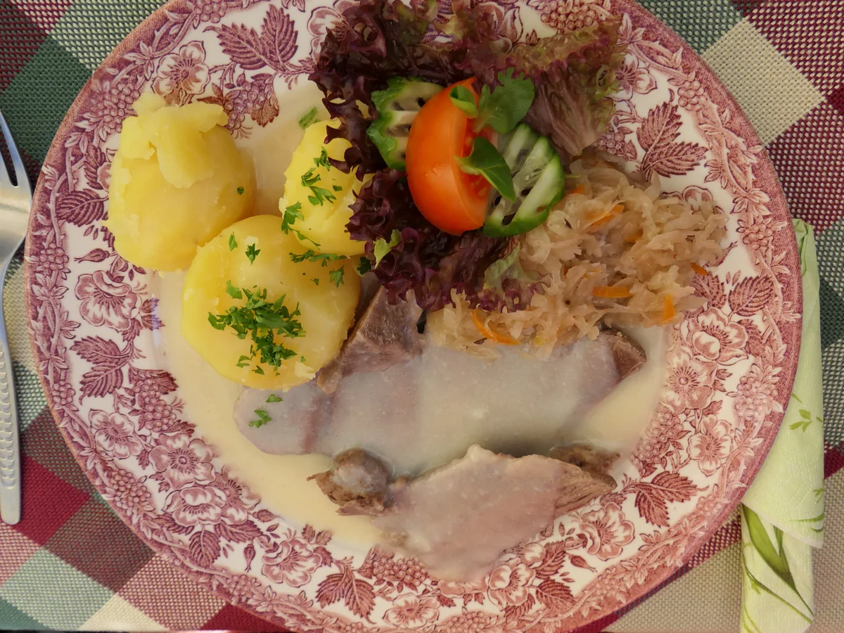 Tafelspitz mit Meerrettichsauce, Salzkartoffeln, Sauerkraut und Salat auf einem gemusterten Teller