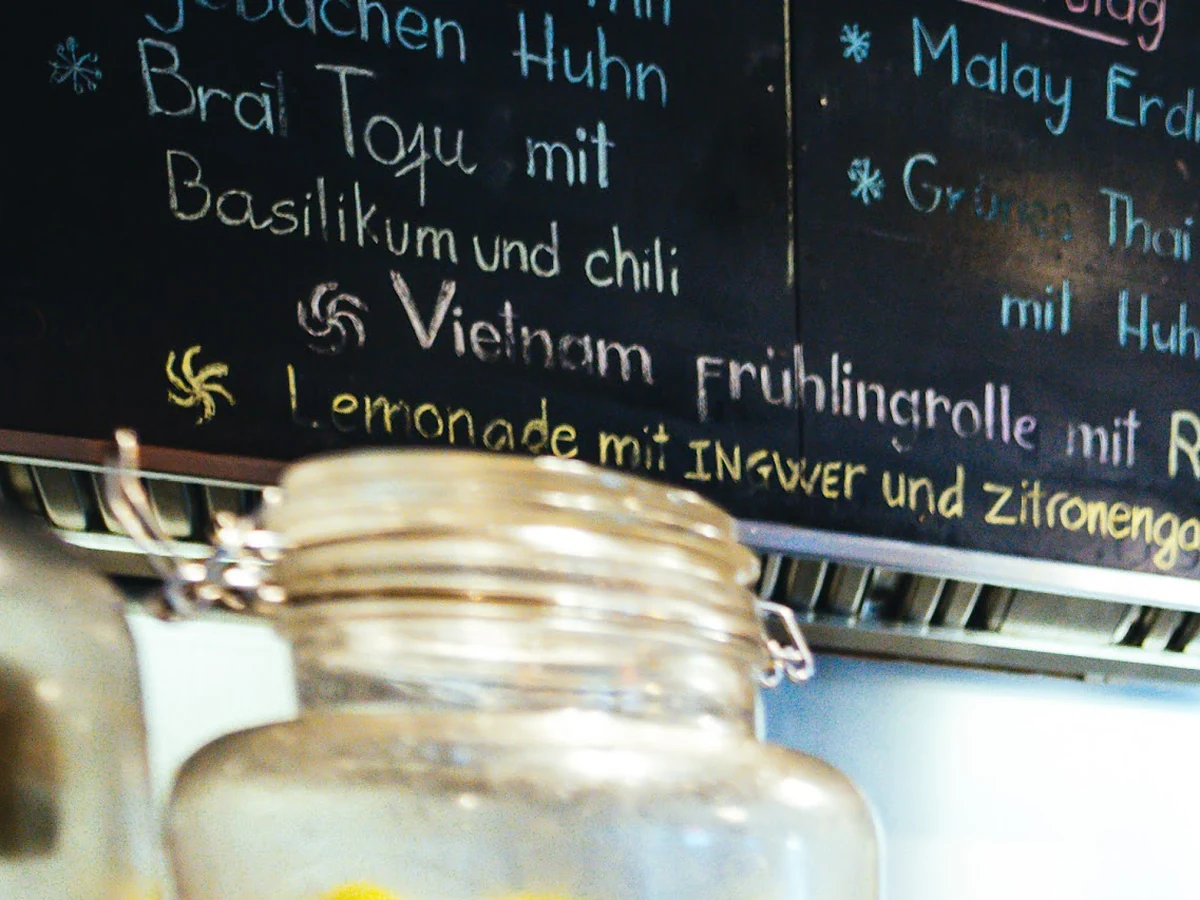 Mit Kreide beschriebene Menüetafel mit Gerichten wie Brat Tofu mit Basilikum, Vietnam Frühlingsrolle und Malay Erdnuss H