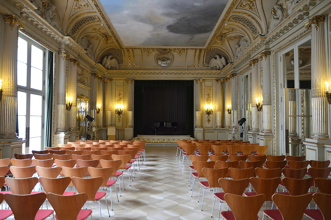 Spiegelsaal aus dem Budge-Palais im Museum für Kunst und Gewerbe mit weiß-goldenem Stuck, Deckengemälde und Stuhlreihen