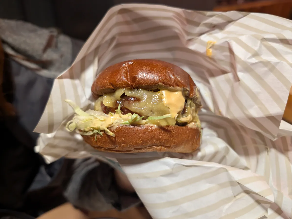 Veganer Burger mit Sauce und Salat in gestreiftem Einwickelpapier