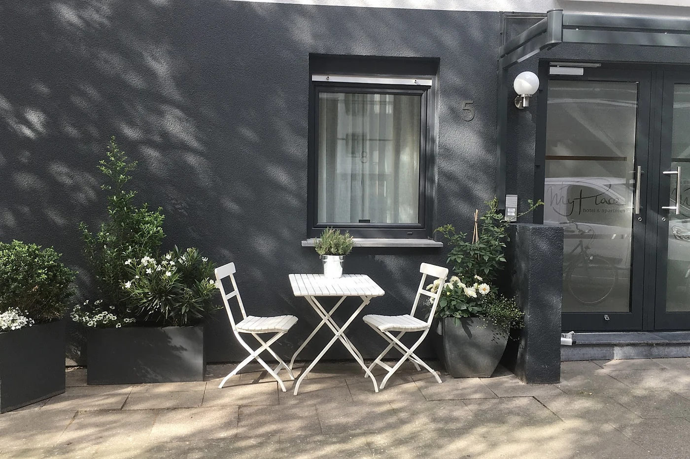 Innenhof mit Bistrotisch und Stühlen vor einer Hauswand