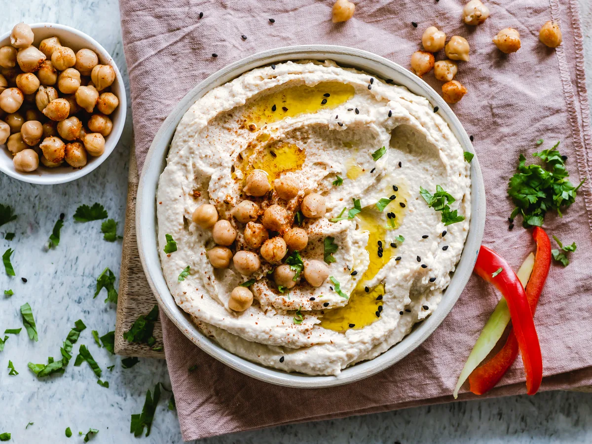 Hummus mit Kichererbsen, Olivenöl, Petersilie und Sesam in einer Schale
