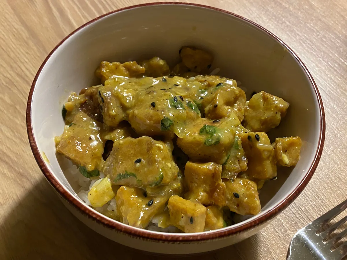 Curry mit Tofuwürfeln und Gemüse, daneben eine Portion Reis
