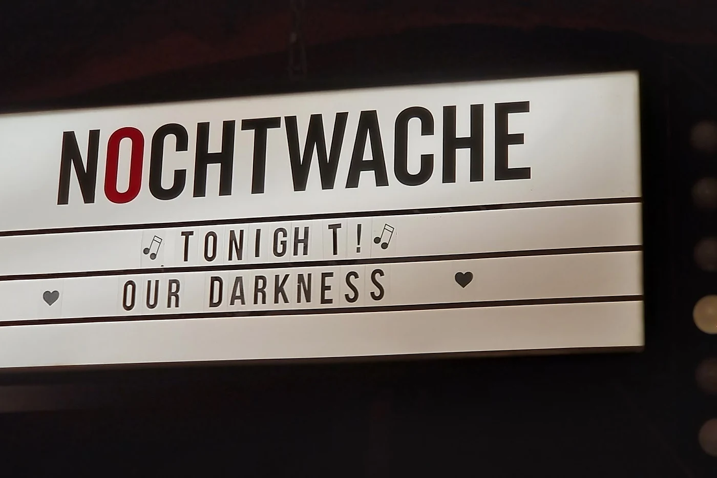 Leuchtkasten mit Stecklettern und der Aufschrift NOCHTWACHE sowie dem Hinweis auf den Auftritt des Abends