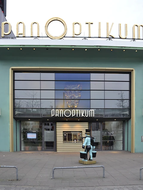 Eingang des Panoptikums mit Vitrinen und Plakaten neben der Tür