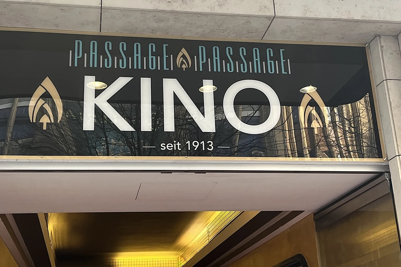 Dunkles Schild über einem Eingang mit dem Schriftzug Passage Passage Kino und dem Zusatz seit 1913