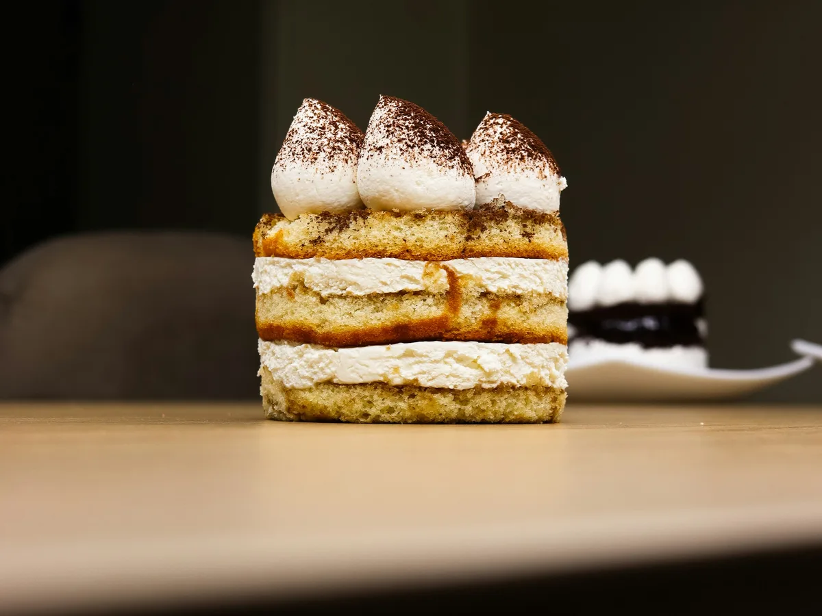 Geschichtetes Tiramisu mit Kakaopulver auf einem Holztisch