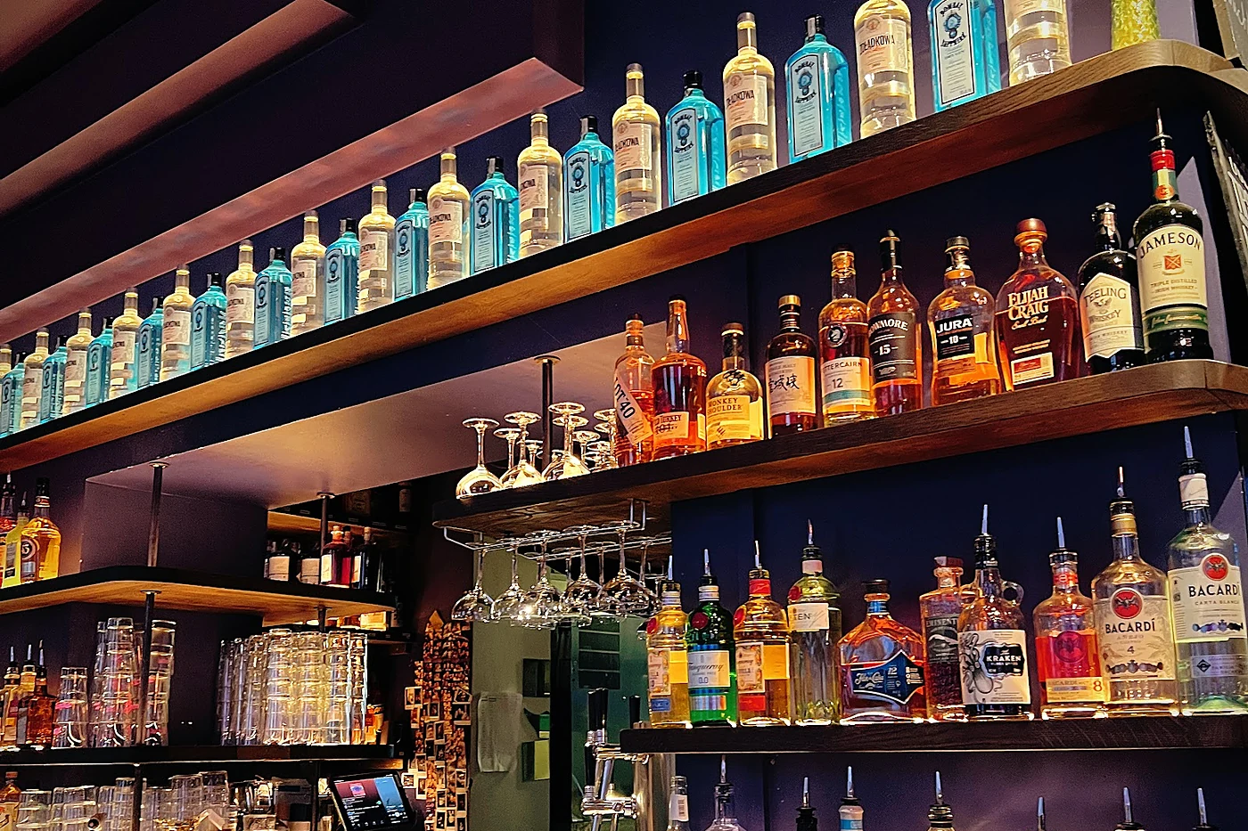 Beleuchtete Flaschenregale hinter dem Tresen der Pelican Bar mit Gin-, Whisky- und Rumflaschen