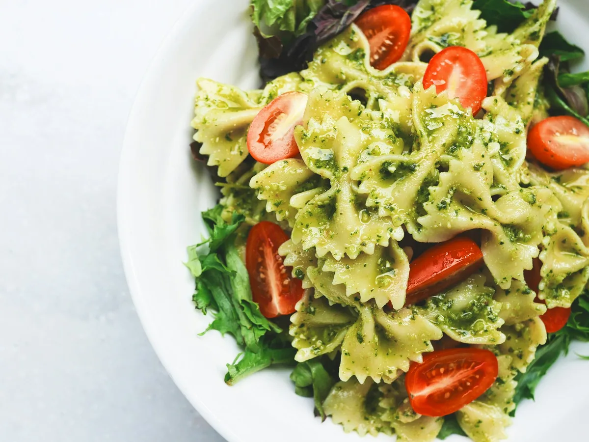 Pesto-Pasta mit Tomatenscheiben auf weißem Teller