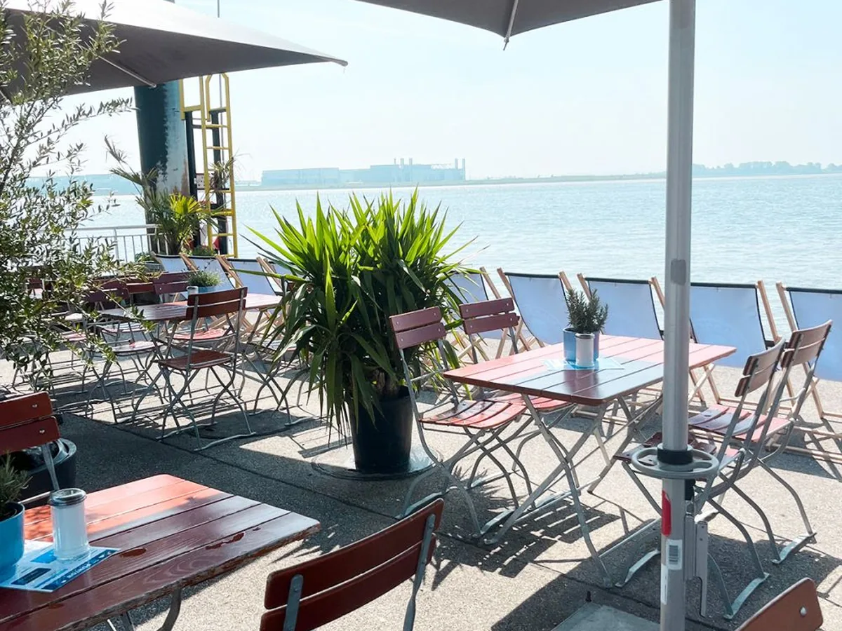 Terrasse mit Sonnenschirm und Stühlen direkt am Elbufer