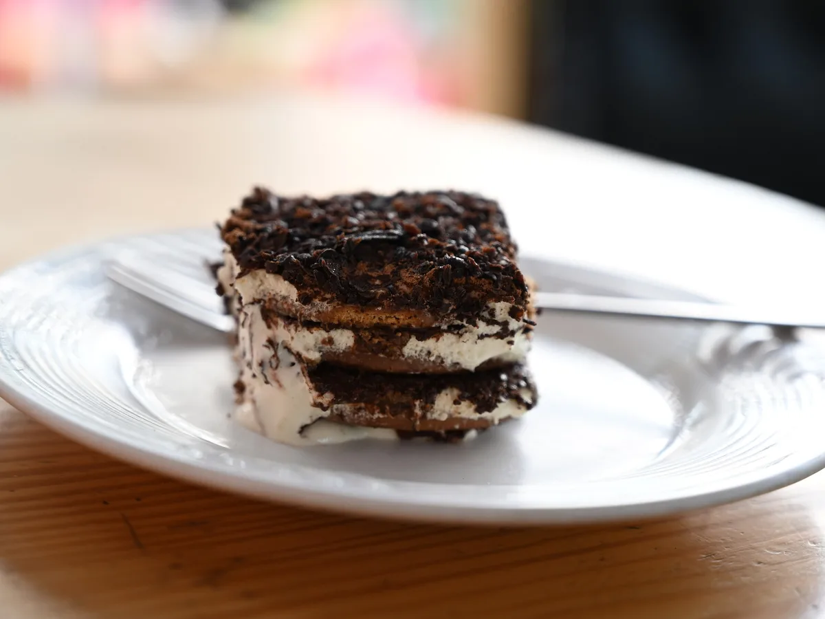 Stück Tiramisu mit Schokoraspeln auf einem weißen Teller