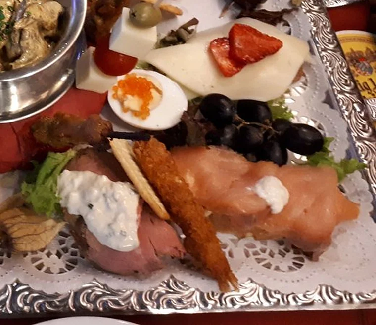 Nahaufnahme der Vorspeisenplatte mit Lachsröllchen, Roastbeef mit Remoulade, Trauben, Käse und Erdbeere