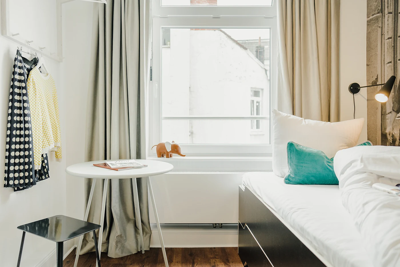 Zimmer mit Bett, Tisch und bodentiefem Fenster