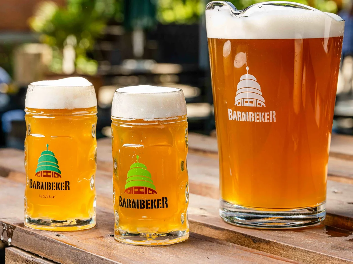 Drei frisch gezapfte Biere auf einem Holztisch im Biergarten