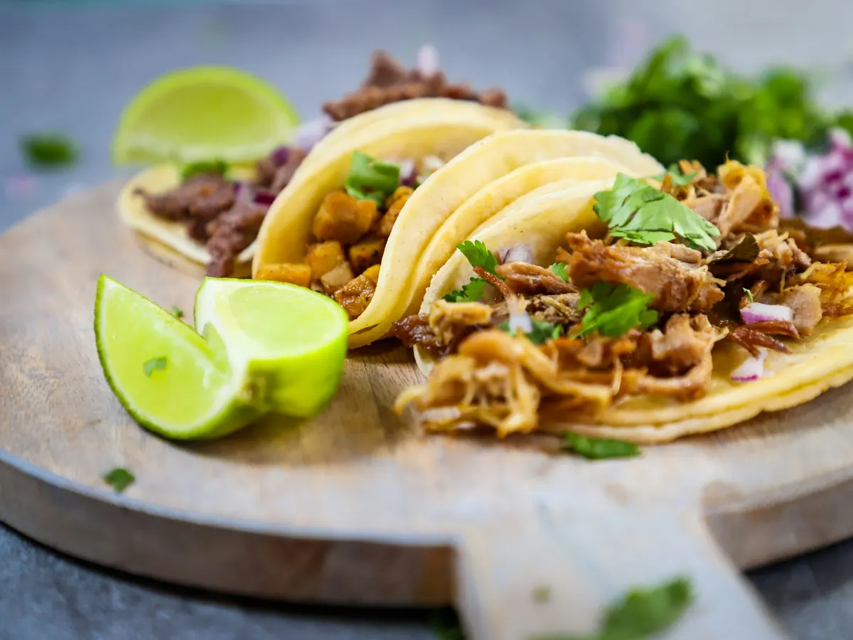 Drei Tacos mit Limette auf einem Holzteller