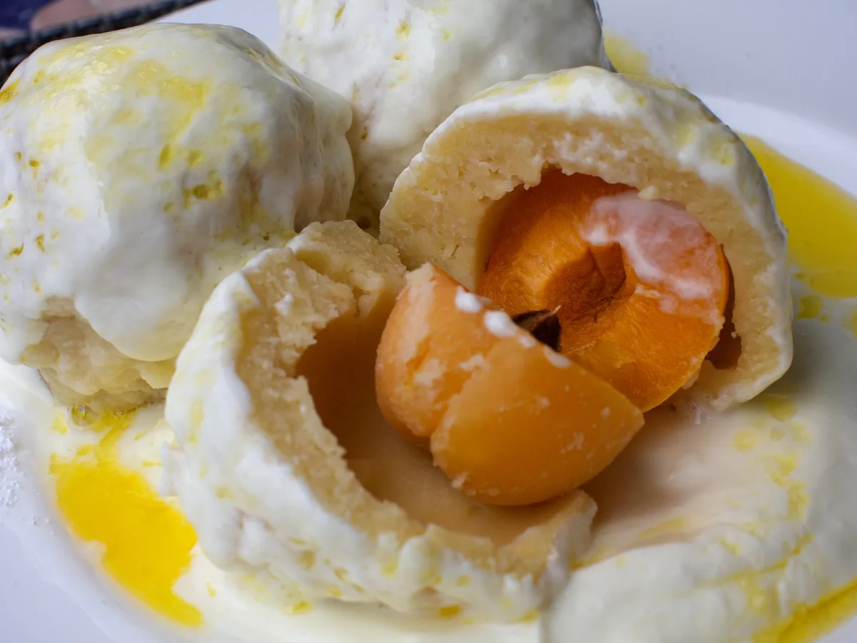 Aufgeschnittene Marillenknödel mit Aprikose im Inneren, dazu Vanillesauce