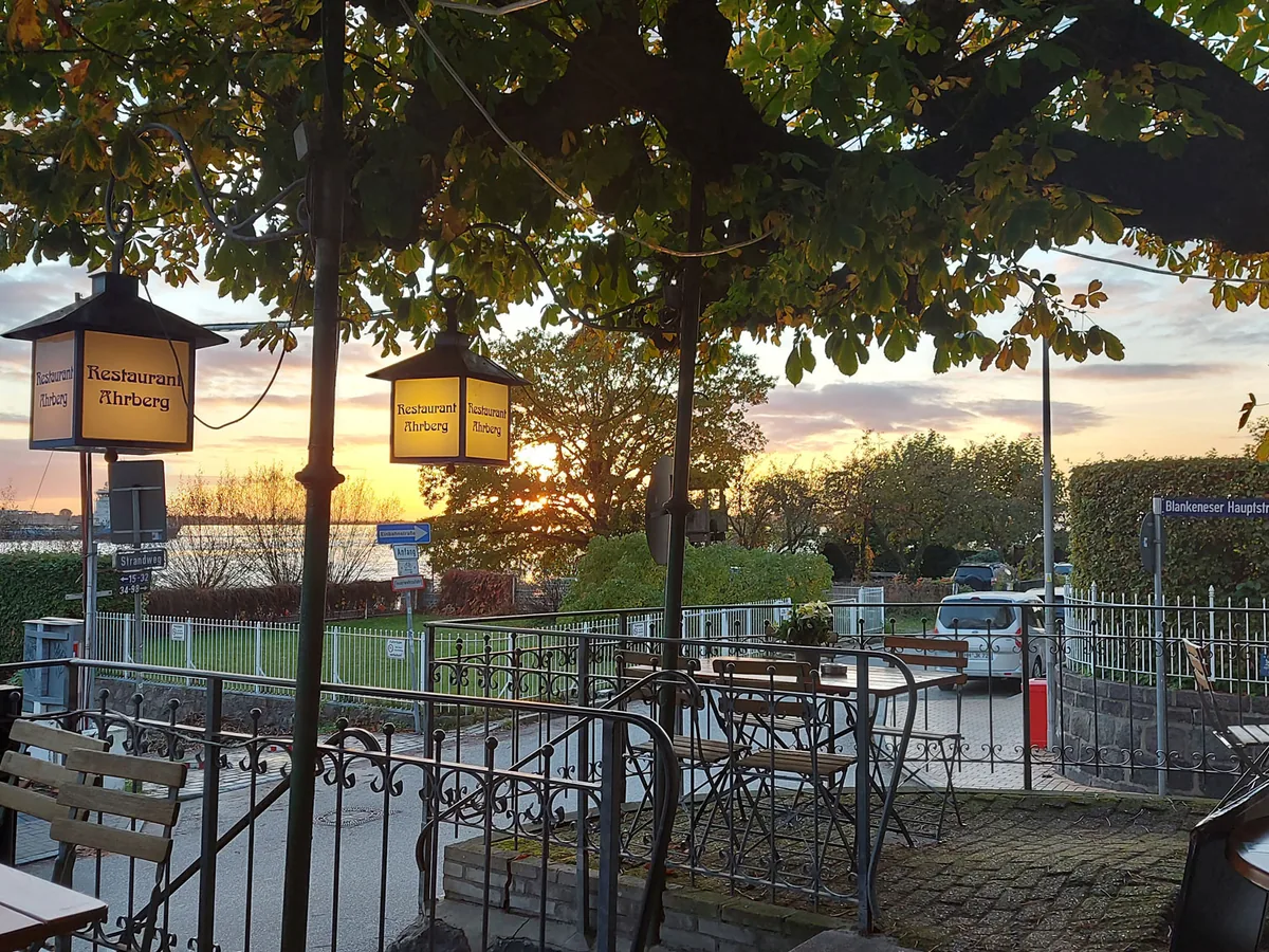 Terrasse mit Tischen und Laterne bei Sonnenuntergang