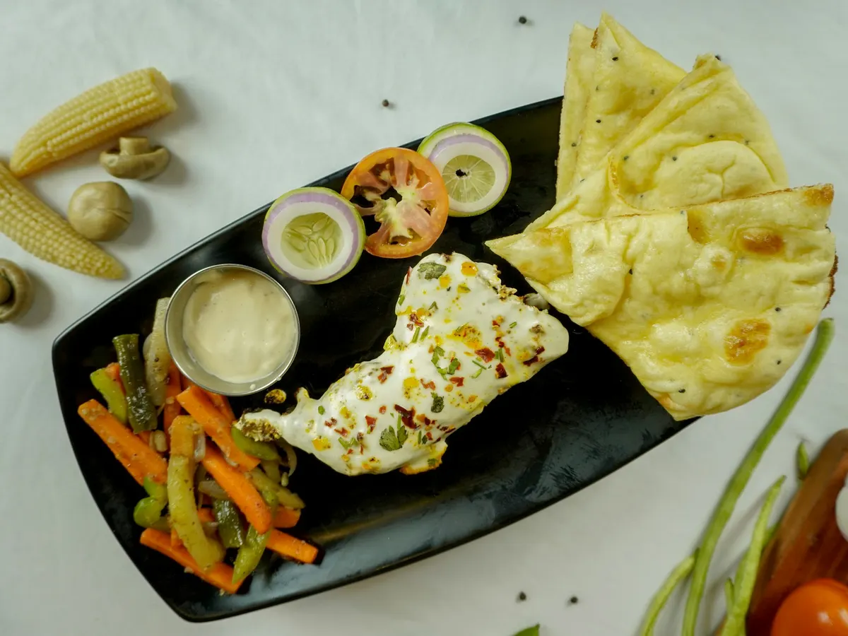 Teller mit Paneer, Naanbrot, Gemüse und Sauce