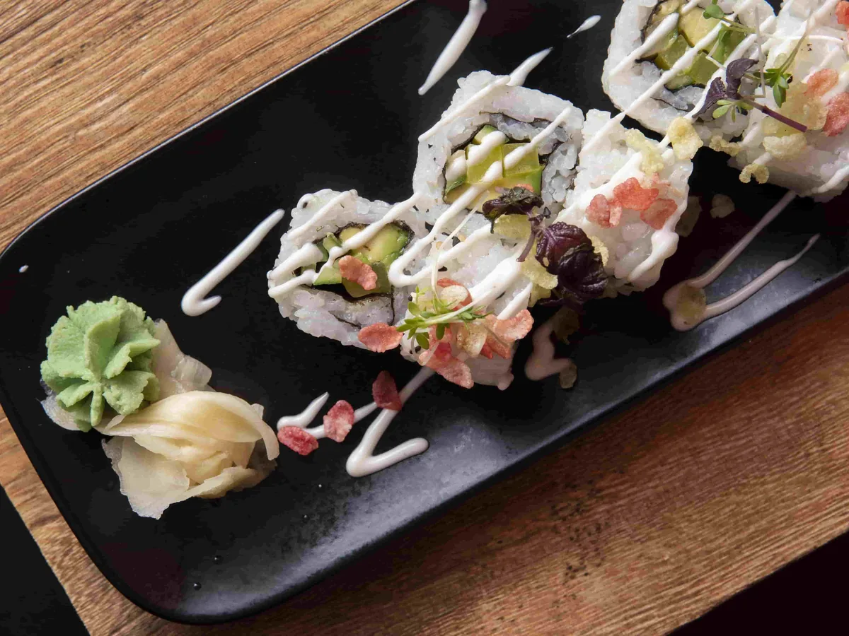 Sushi-Rollen auf einem dunklen Holzbrett mit BOK-Logo