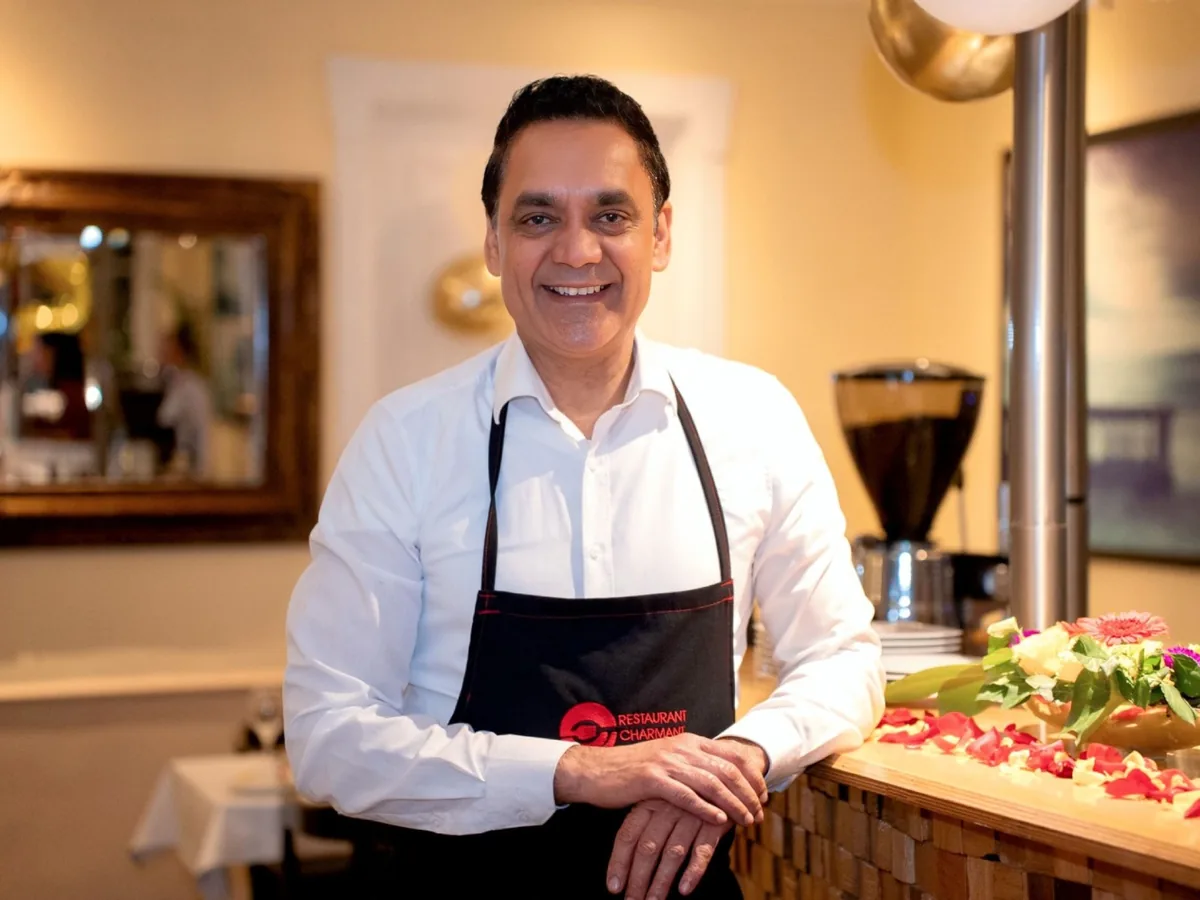 Gastgeber des Restaurant Charmant mit Schürze an der Theke