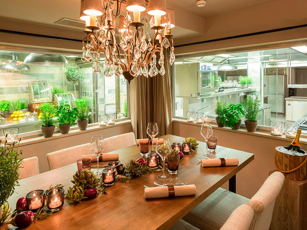 Chefs Table mit Kräutern und offener Küche im Hintergrund