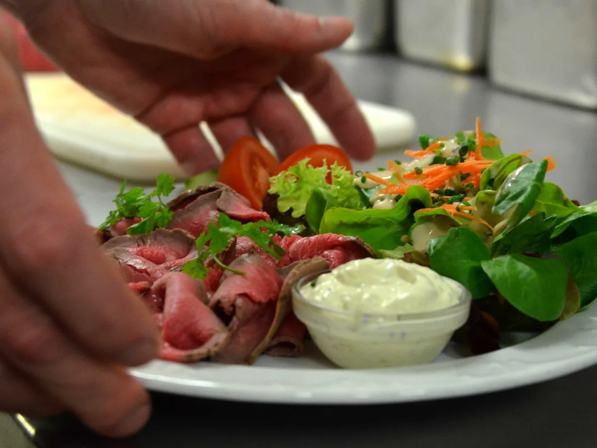Teller mit Roastbeef, Blattsalat und Remoulade wird serviert