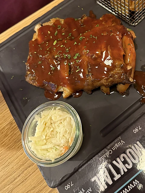 Spareribs mit Sauce auf einem Schieferbrett, daneben ein Dip