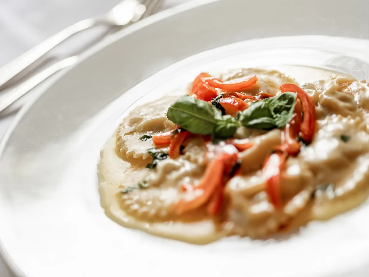 Hausgemachte Ravioli mit Tomaten und Basilikum auf weißem Teller