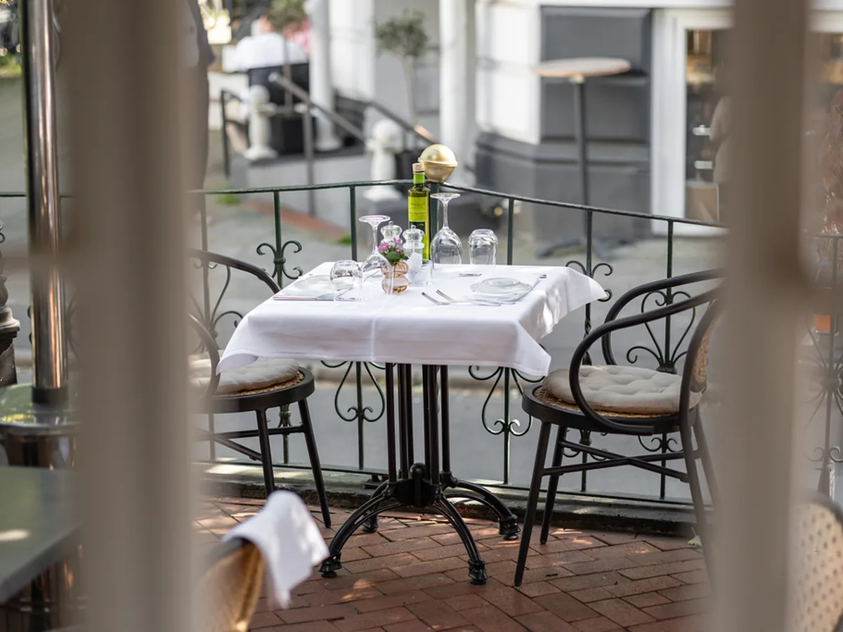 Eingedeckter Tisch mit weißer Decke auf der Terrasse des Portonovo