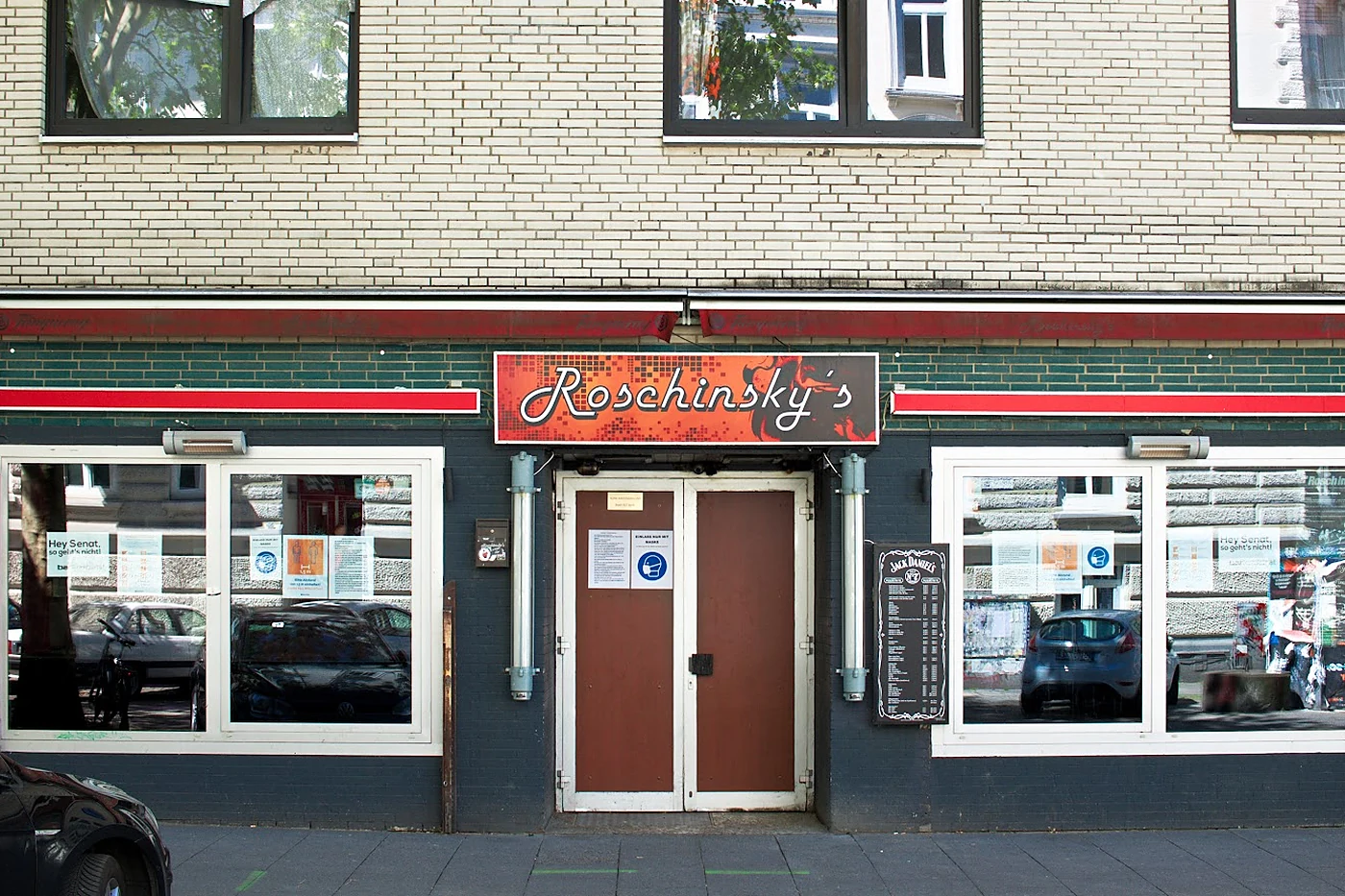 Fassade von Roschinsky’s am Hamburger Berg mit rotem Leuchtschild über den Fenstern und brauner Eingangstür
