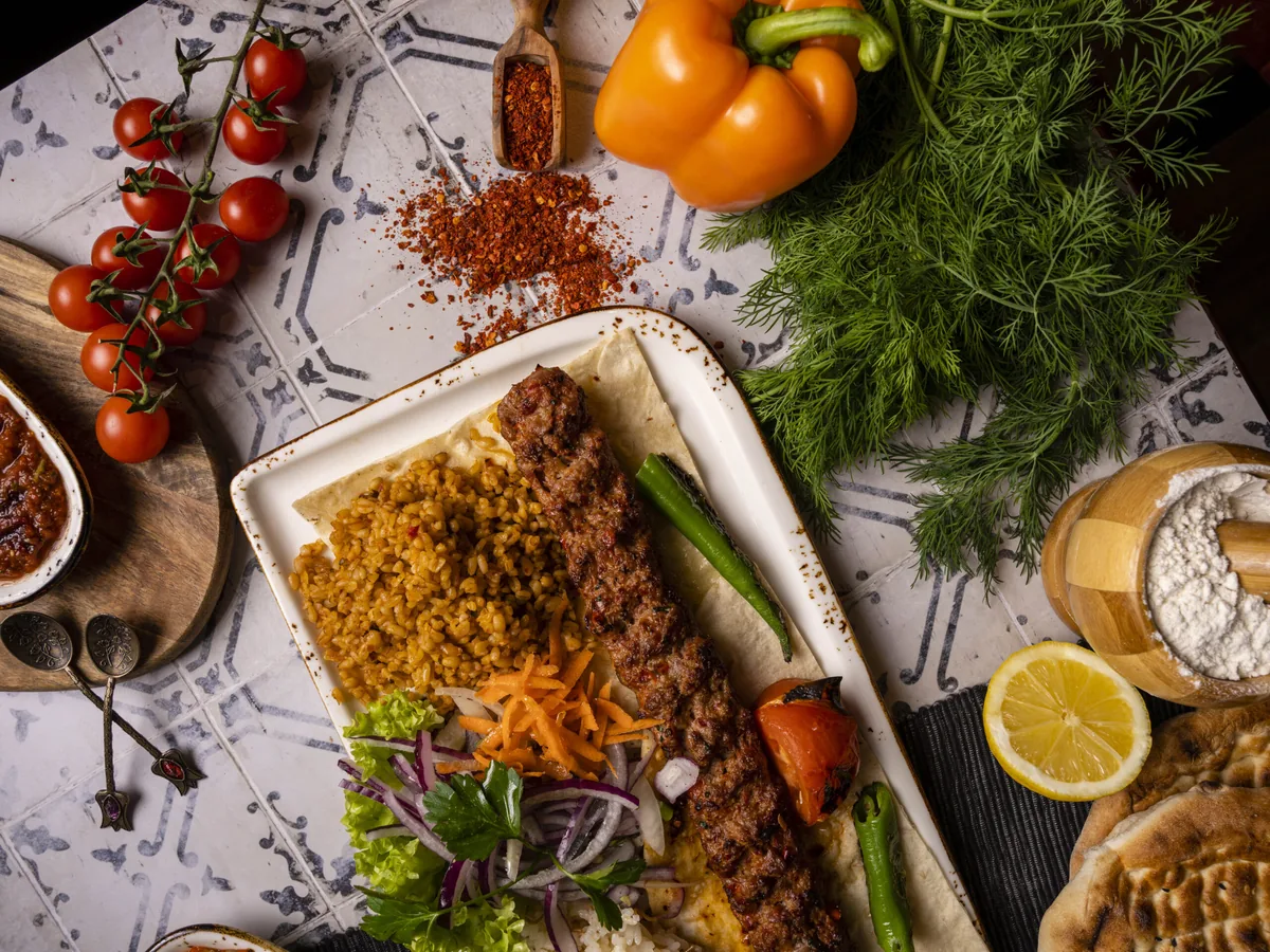 Kebab mit Bulgur, Paprika und Kräutern auf weißem Blech