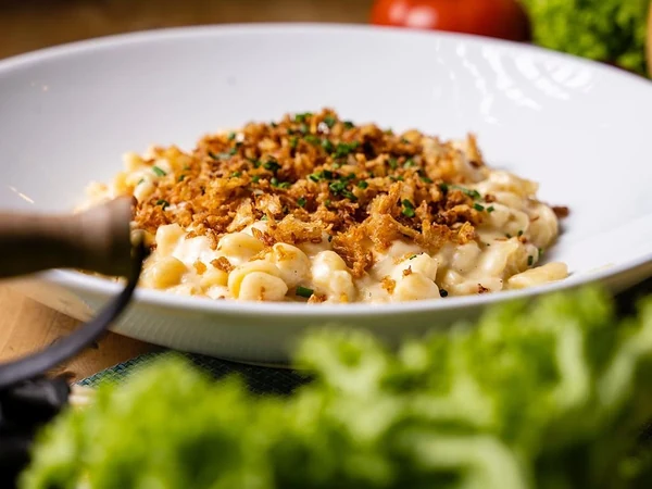 Käsespätzle mit Röstzwiebeln und Schnittlauch in einer weißen Schale