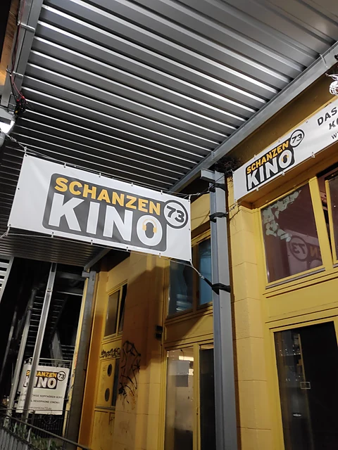 Banner mit der Aufschrift Schanzen Kino 73 unter einem Vordach neben einer gelben Hausfassade