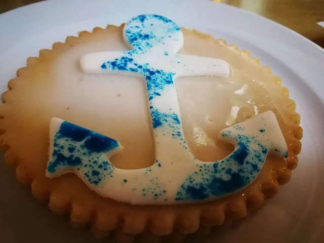 Runde Tarte mit weißer Zuckerglasur und blau gesprenkeltem Anker aus Fondant