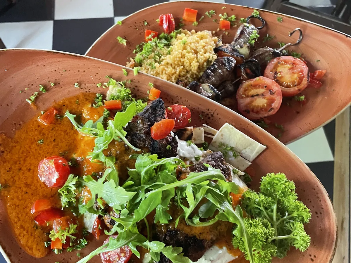 Zwei Schalen mit Salat, Couscous und Tomaten auf Schachbrettboden