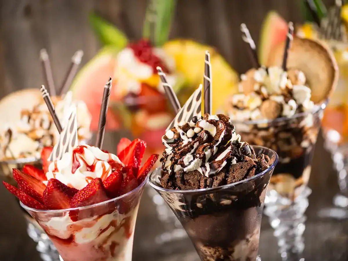 Zwei Eisbecher mit Sahne, Erdbeeren und Schokolade