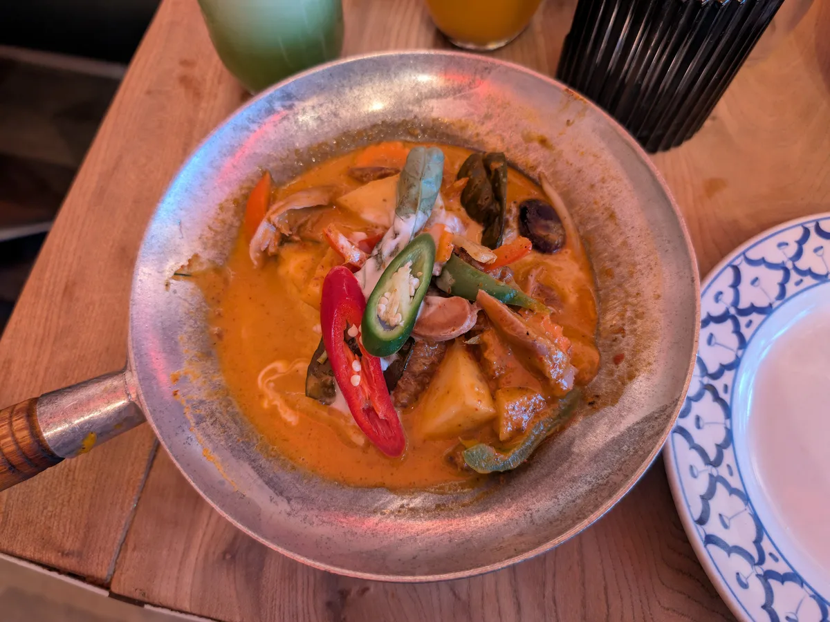 Rotes Thaicurry mit Ente, Chilischoten und Gemüse in einer Servierpfanne