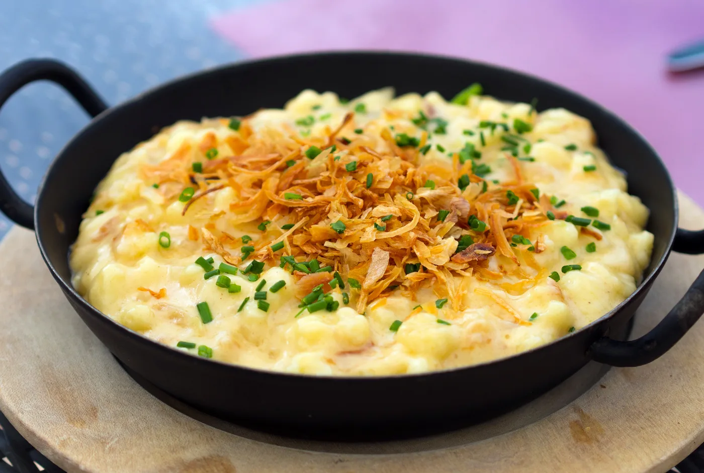 Käsespätzle mit Röstzwiebeln und Schnittlauch in einer schwarzen Pfanne