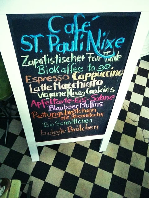 Kreidetafel des Café St. Pauli Nixe mit Angebot: zapatistischer Fair-Trade-Biokaffee, vegane Nixen-Cookies, Apfeltarte, 