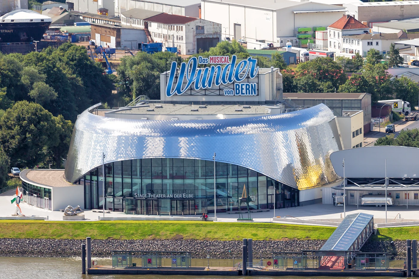 Die geschwungene Metallfassade des Theaters an der Elbe am Hafenufer