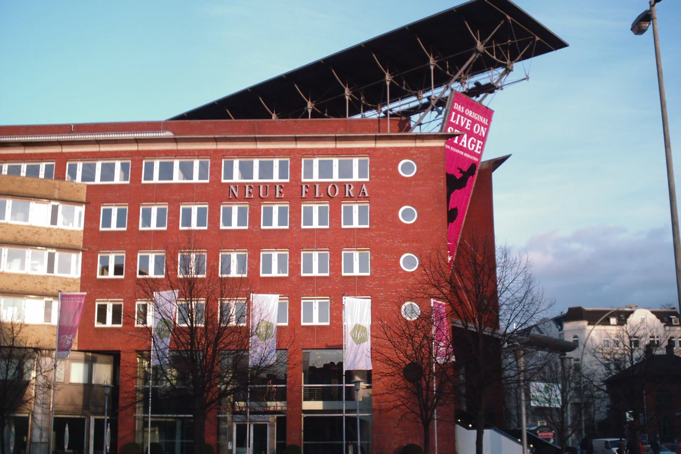 Seitenansicht des Theaters mit Bahntrasse und kahlen Bäumen davor