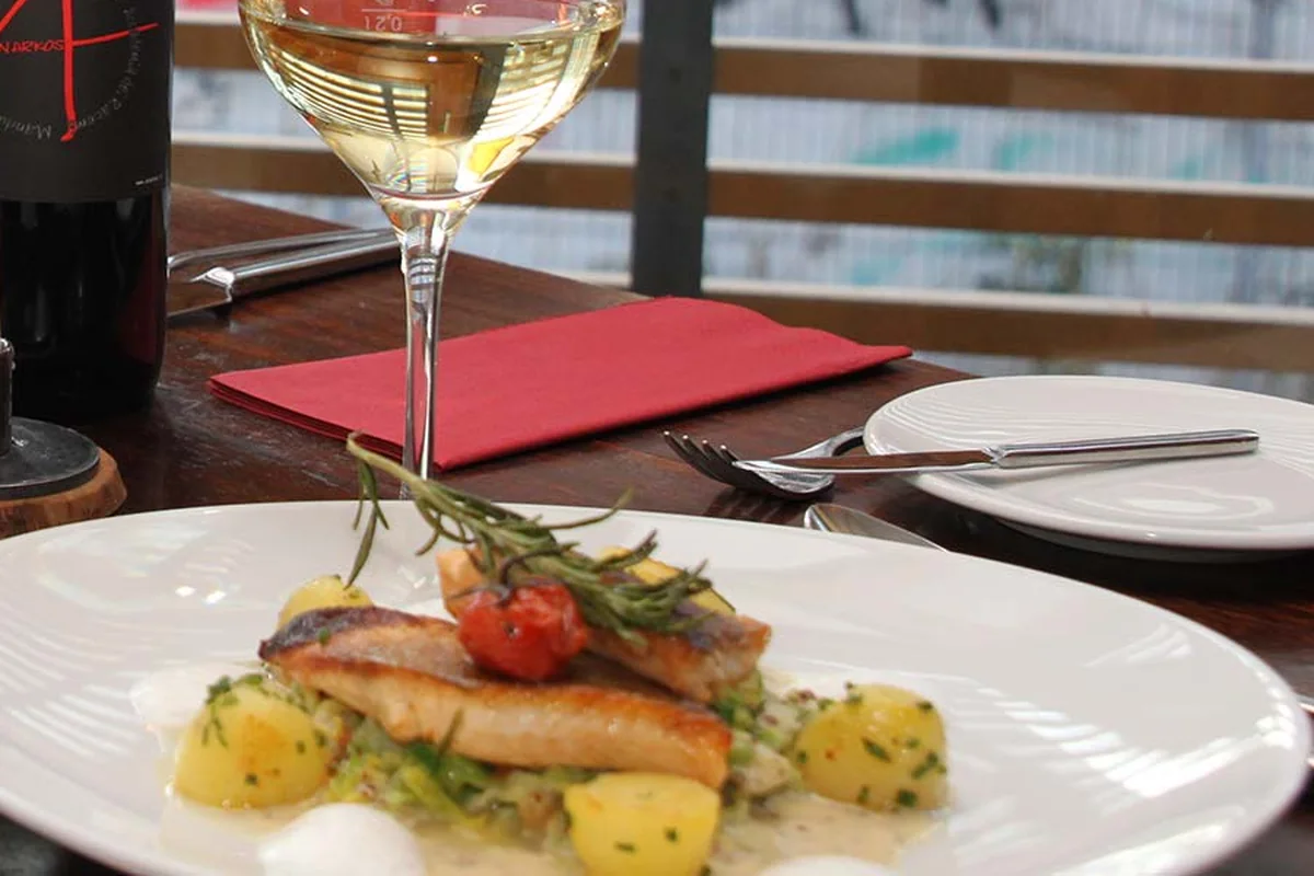 Teller mit gebratenem Fischfilet auf Kartoffeln mit Kräutern, Kirschtomate und Rosmarinzweig