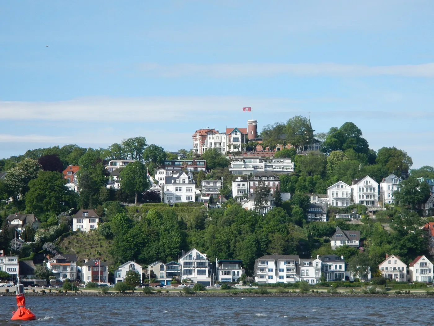 Der Süllberg von der Elbe aus, oben das Ausflugslokal mit Turm und Hamburger Flagge