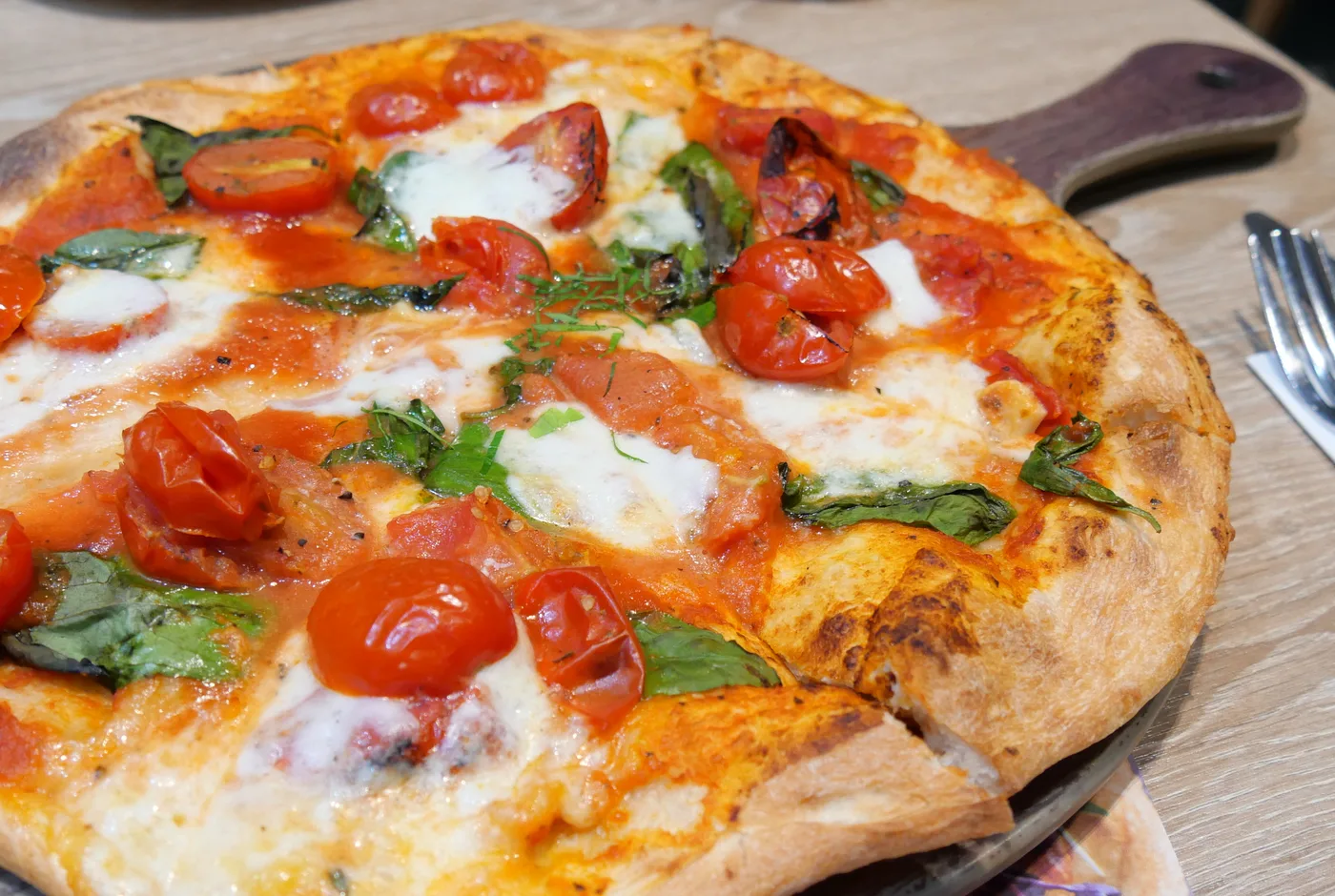 Pizza mit Tomaten, Mozzarella und Basilikum auf einem Holzbrett