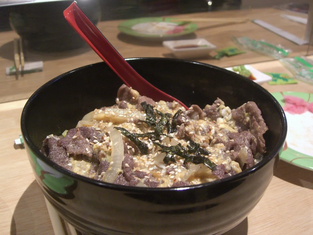 Reisschale mit Fleisch, Ei und Nori in dunkler Keramikschale