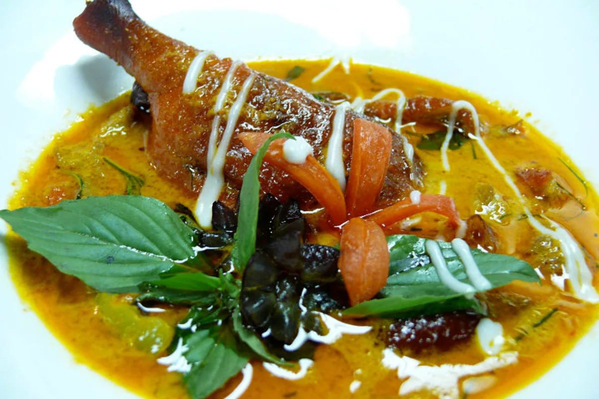 Knusprige Entenkeule in gelbem Curry mit Thai-Basilikum, Tomate und Kokosmilch