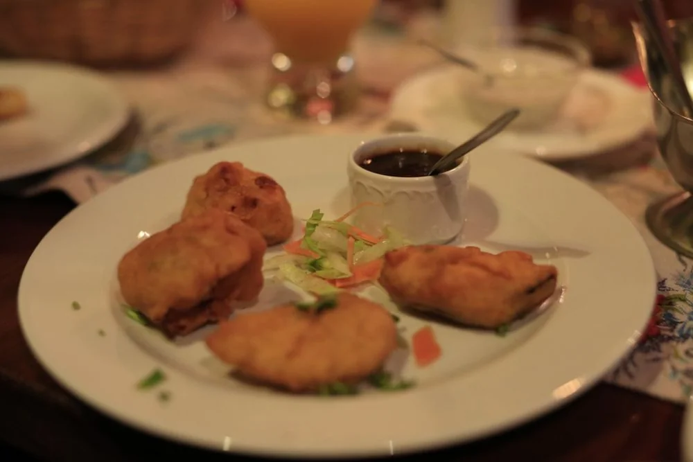 Teller mit frittierten Pakora und Samosa, dazu ein Schälchen dunkler Dip