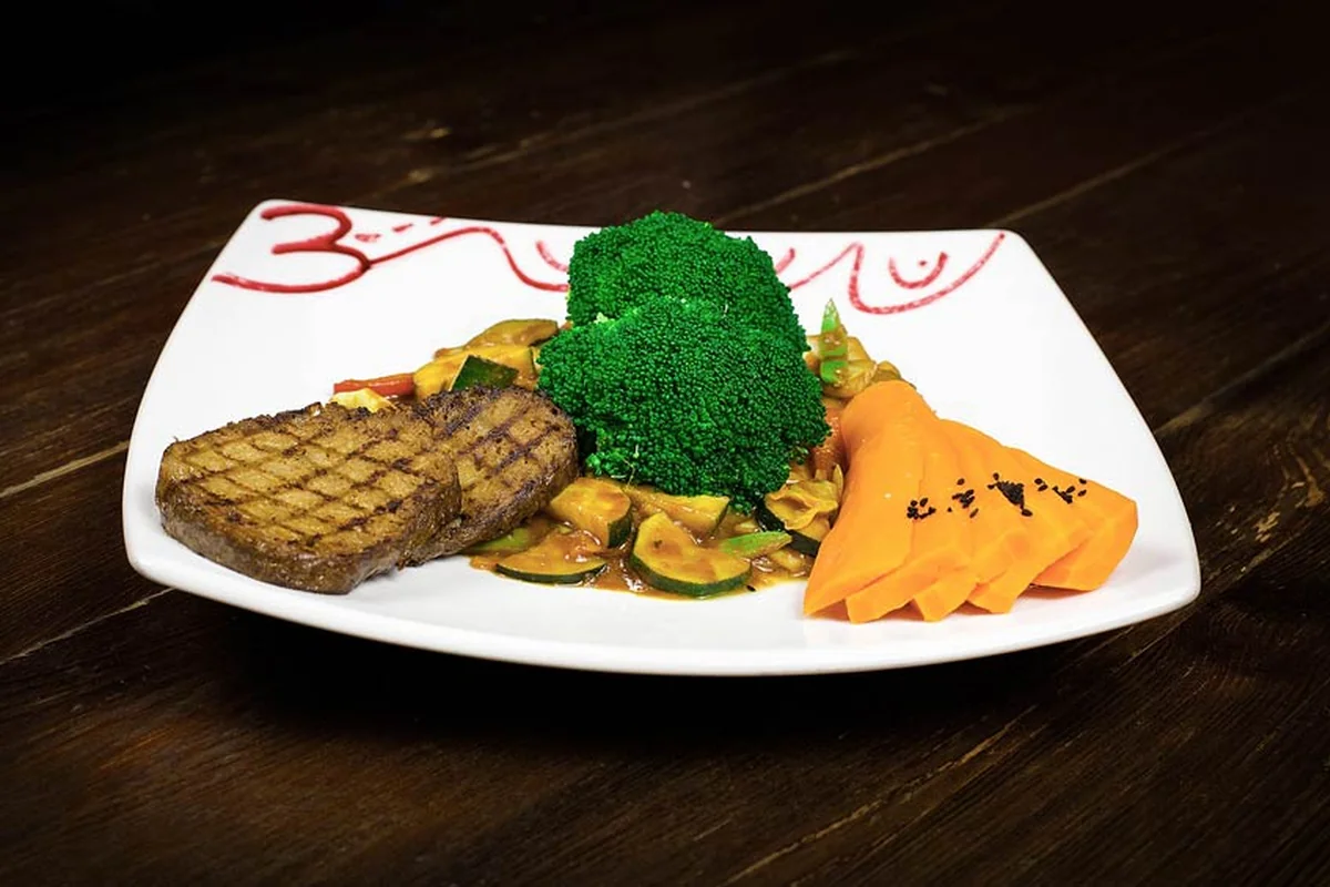 Gegrillte Seitan-Scheiben mit Gemüse in Currysauce, Brokkoli und Papayaspalten