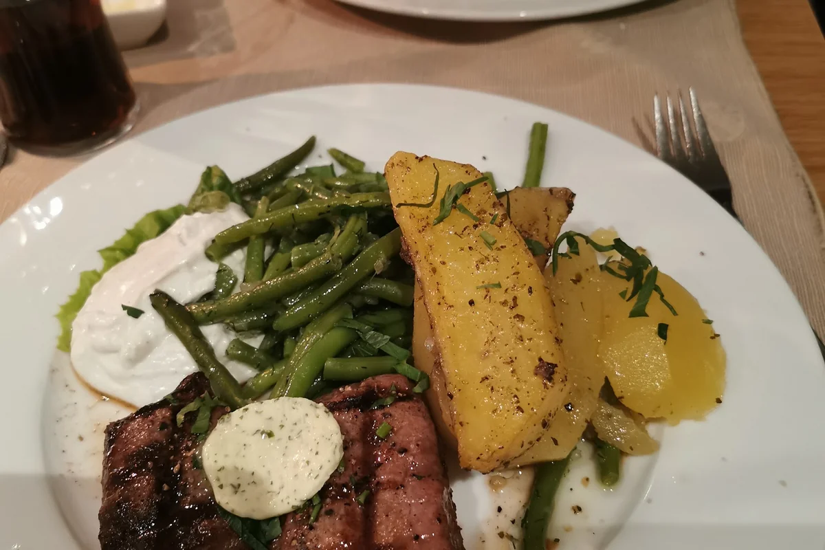 Gegrilltes Steak mit Kräuterbutter, grünen Bohnen, Ofenkartoffeln und Tzatziki
